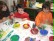 Zwei Kinder und eine Kindergärtnerin malen gemeinsam mit Wasserfarben. 