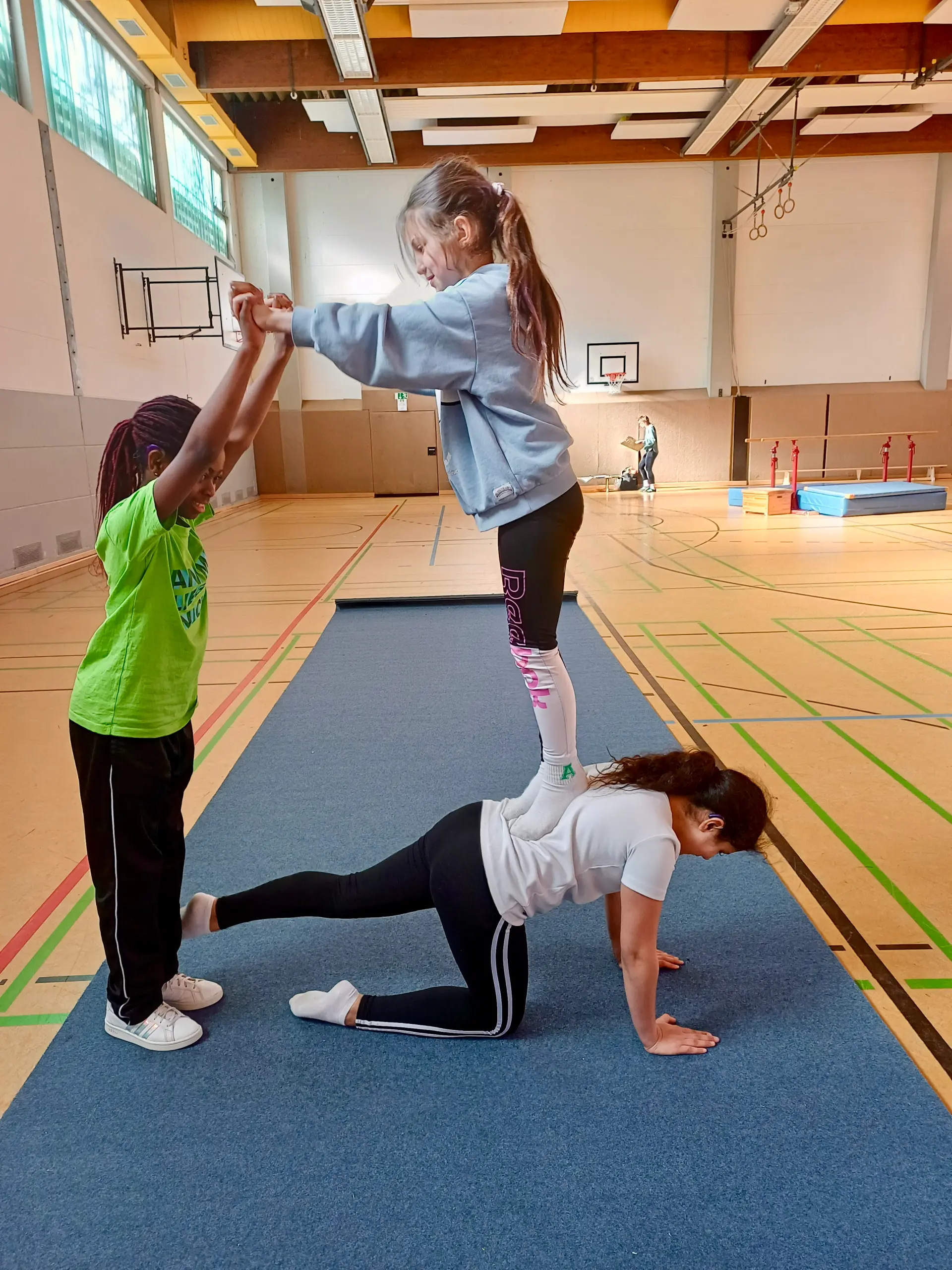drei grundschülerinnen formen in ansätzen eine pyramide