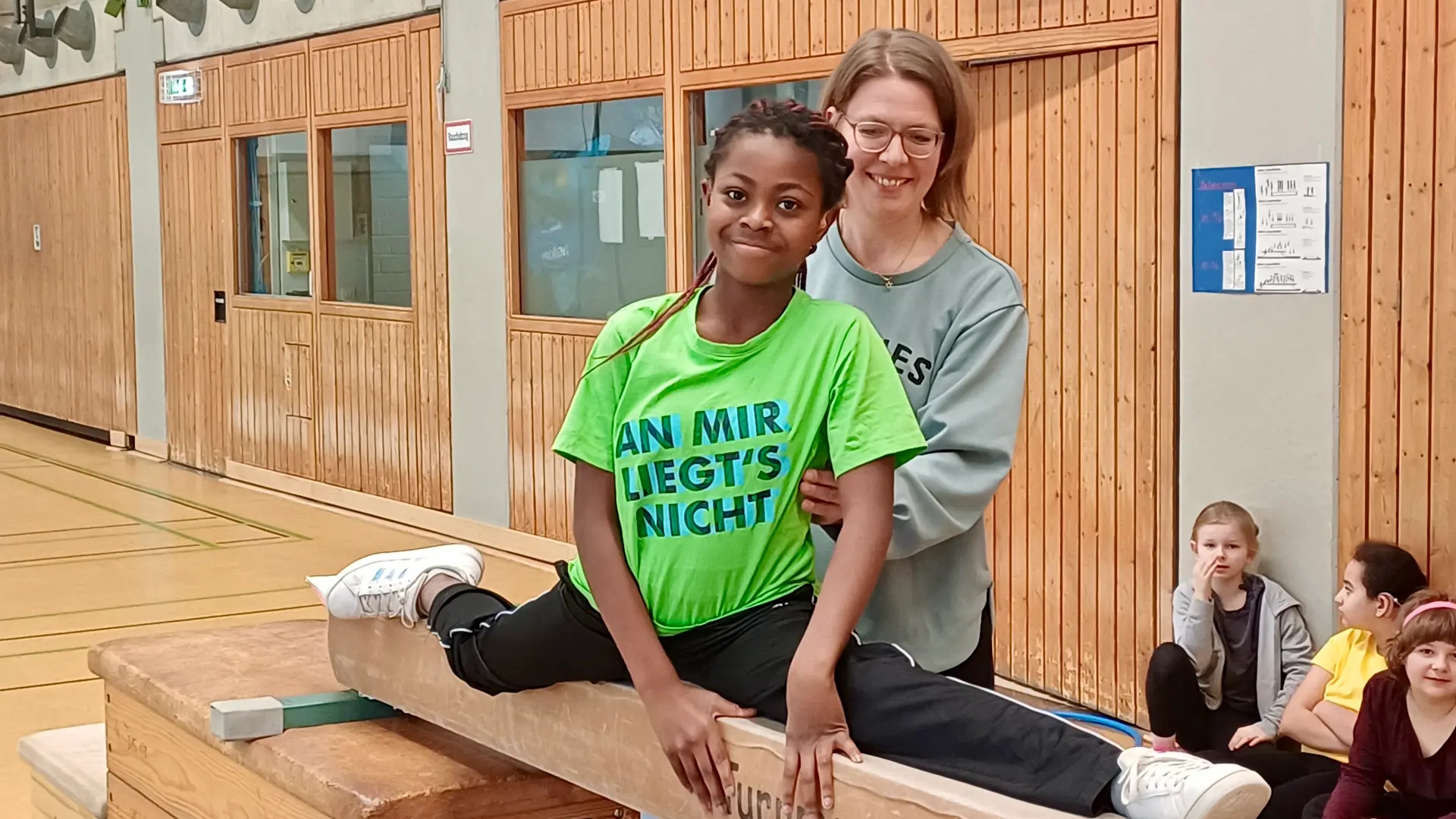 Eine Hand voll Menschen läuft eine flache Skipiste bei Tag hoch. Im Hintergrund ist eine kleine Hütte zu erkennen.
