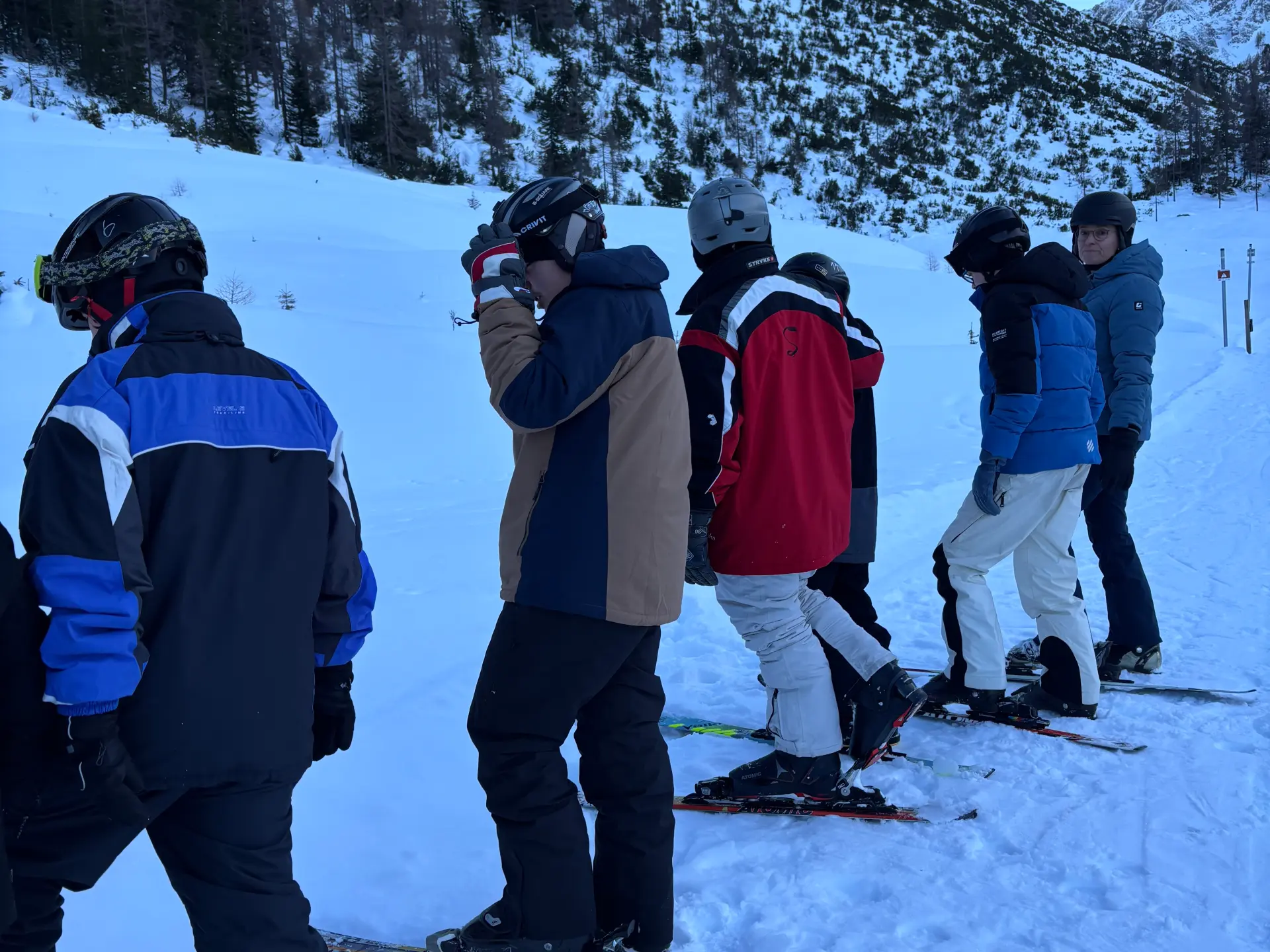 Mehrere Schüler in Skikleidung nebeneinander in einer Reihe und blicken zum linken Bildrand.